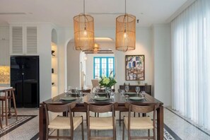 A dining area with a long table, chairs, and hanging light fixtures. - domdomHOUSE Villa - 1min to beach (Ha Long)