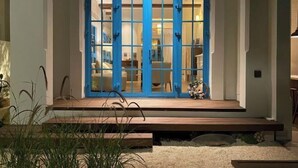 A modern entrance with a blue door, a wooden bench, and a stone wall. - domdomHOUSE Villa - 1min to beach (Ha Long)