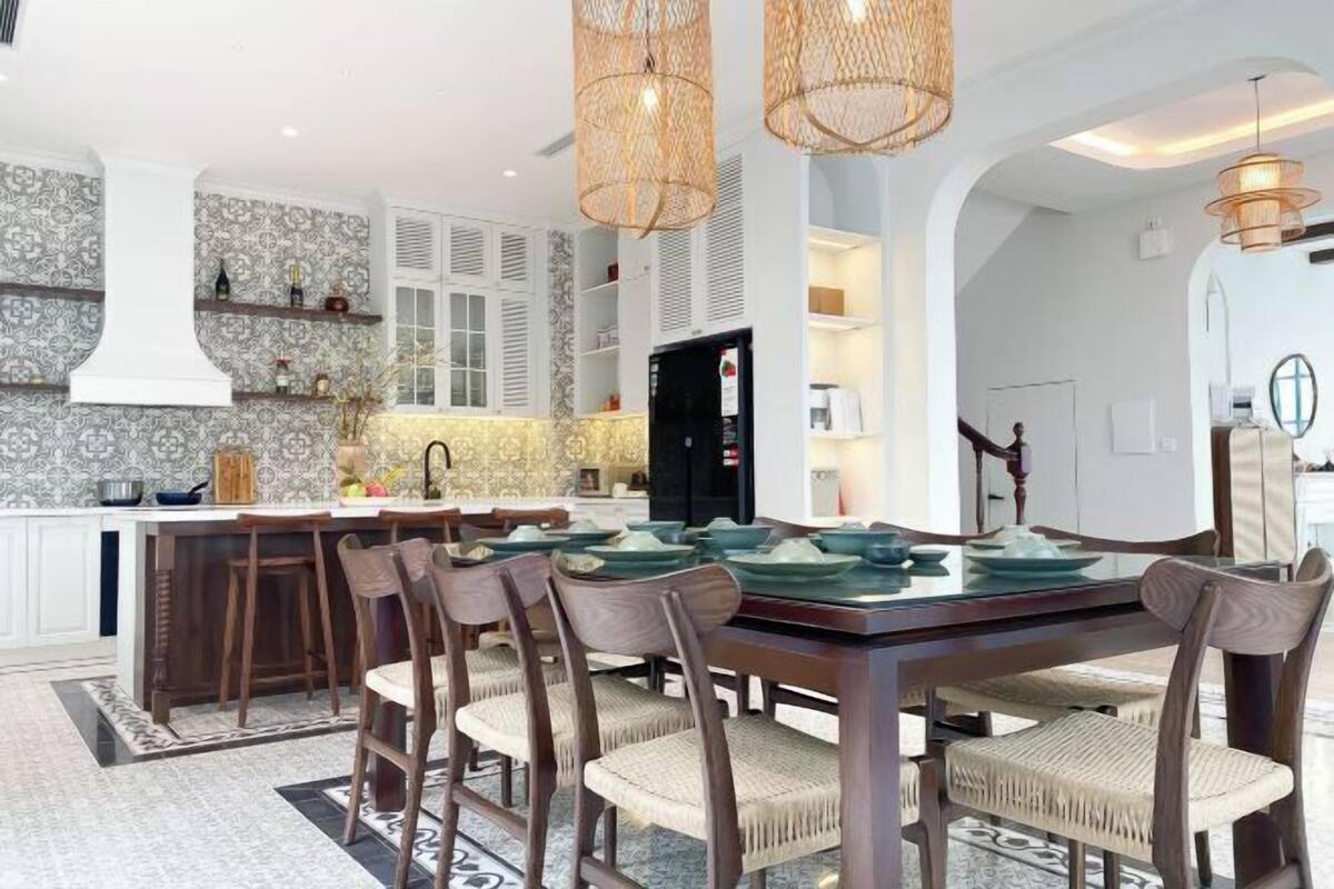 A modern kitchen with a central island, bar stools, and a dining table set for six.