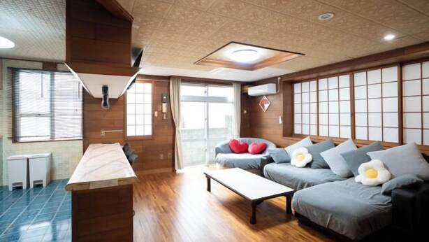 A modern interior with a wooden floor, a sofa with egg-shaped pillows, and a traditional Japanese shoji screen wall. - DAIJUN HOTEL (Naha)