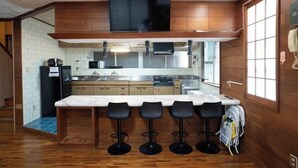 A compact kitchen with a wooden countertop, a built-in stove, and a TV mounted above the counter. - DAIJUN HOTEL (Naha)