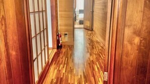 A hallway with wooden flooring and a fire extinguisher on the wall. - DAIJUN HOTEL (Naha)