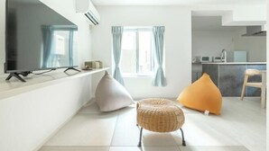 A modern living room with a flat-screen TV, a sofa, and a chair. - Downtown Mix (Tokyo)