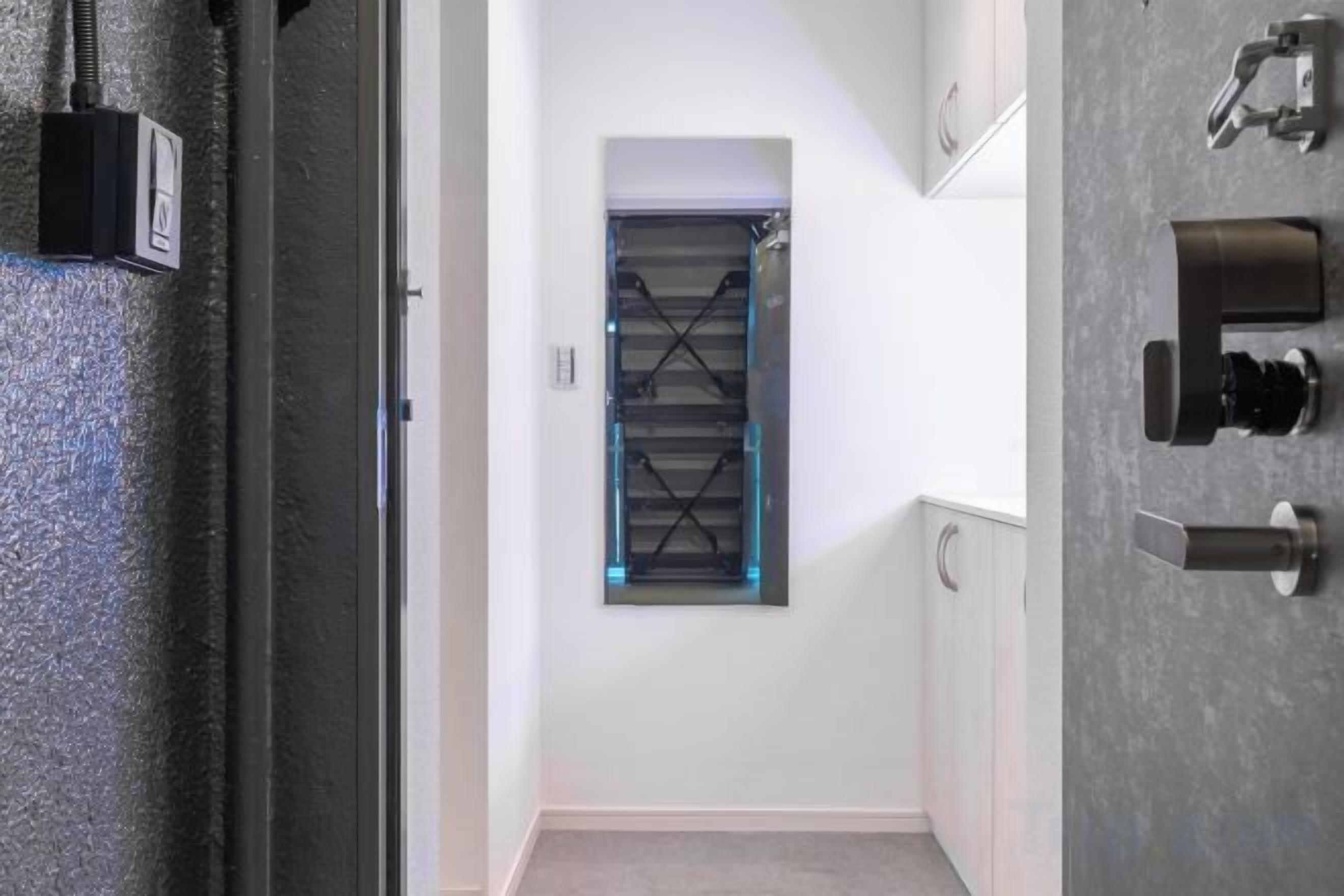 A hallway with a door, a wall-mounted light fixture, and a door handle.