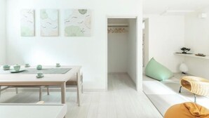 A minimalist room with a wooden table set for tea, a sofa with cushions, and a door leading to a closet. - Downtown Mix (Tokyo)