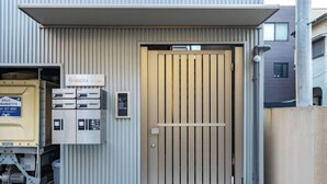 A building entrance with a beige door, a sign reading "Rinescita," and a security keypad. - Downtown Mix (Tokyo)