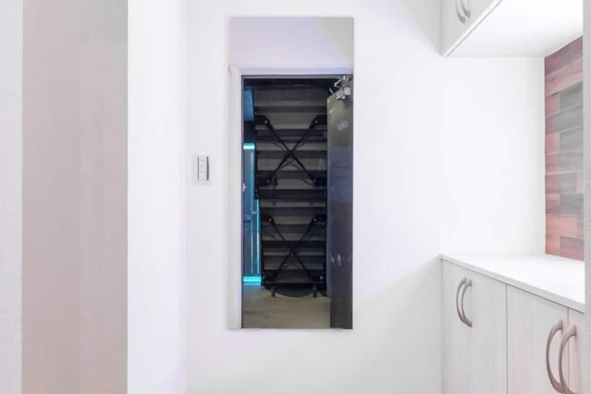 Ein Flur mit einer Spiegelwand, einer Treppe und einem weißen Schrank mit Rundgriffen.
