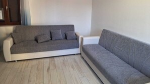 A living room with two grey sofas, a white armchair, and a wooden floor. - Starlight Apartment (Garbagnate Milanese)