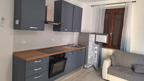 A compact kitchen with grey cabinets, a wooden countertop, and a built-in oven. - Starlight Apartment (Garbagnate Milanese)