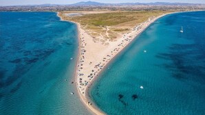 An aerial view of a coastal area with a beach, clear blue waters, and distant mountains. - Lux Mint Apartment - A Modern Luxury Place With Sea View (Thermaikos)
