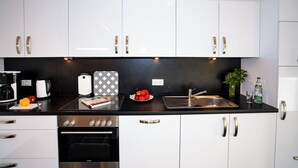 Une cuisine moderne avec des meubles blancs, des appareils en acier inoxydable et un plan de travail noir.