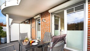Une terrasse avec une table dressée pour deux personnes, une chaise et une petite plante.