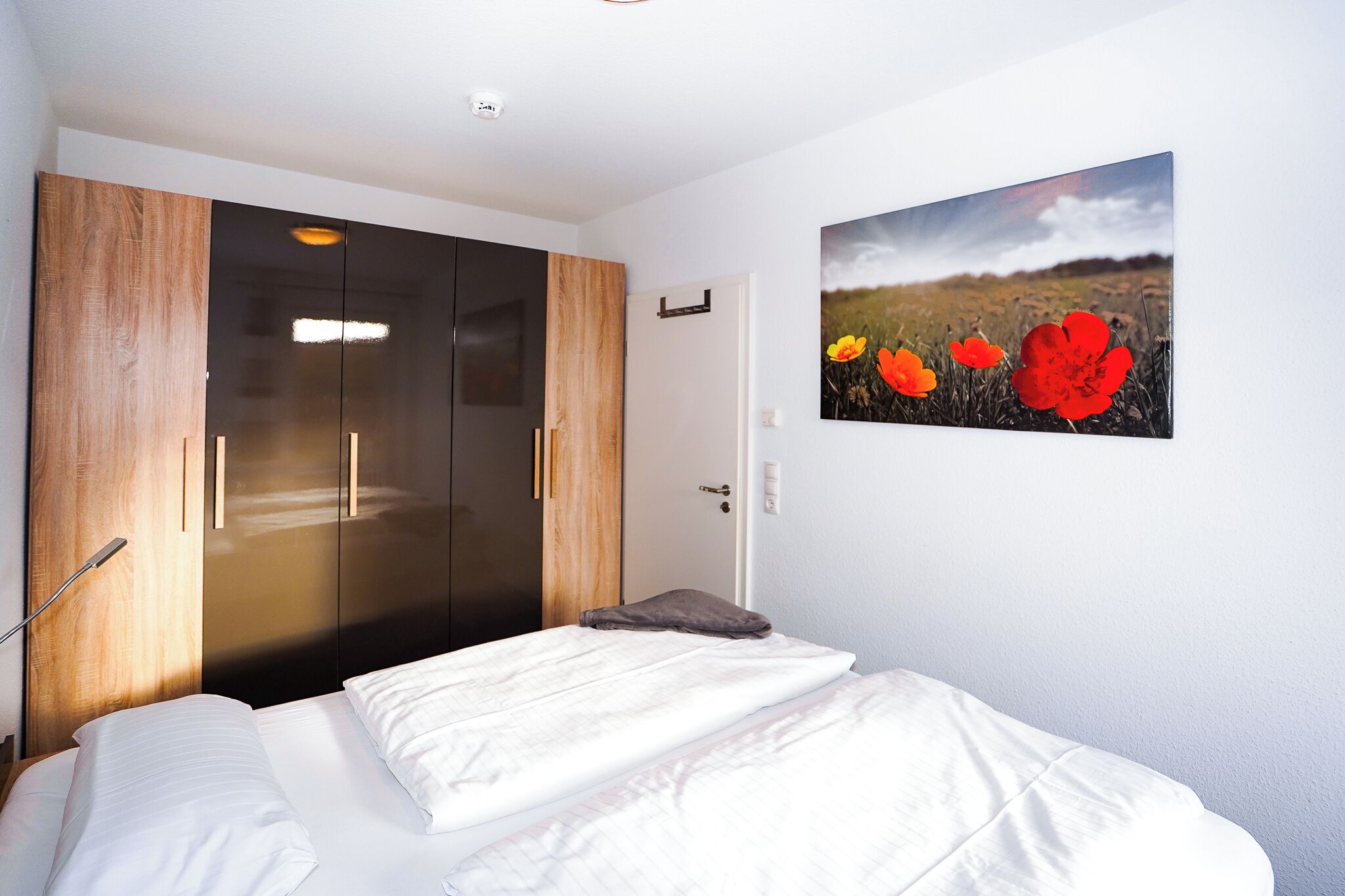 Un dormitorio con una cama, un armario de madera y una puerta.