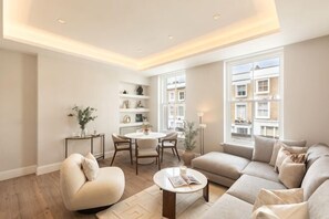 A modern living room with a sofa, coffee table, and dining area. - 313 Premium Maisonette (London)