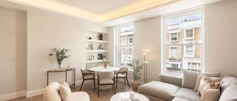 Uma sala de estar moderna com sofá, poltrona, mesa de centro e um espaço de jantar com cadeiras e mesa.