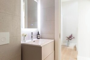 A modern bathroom with a white sink, a mirror, and a bottle of hand soap. - 313 Premium Maisonette (London)