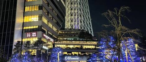 Um edifício moderno com letreiros iluminados e uma torre imponente.