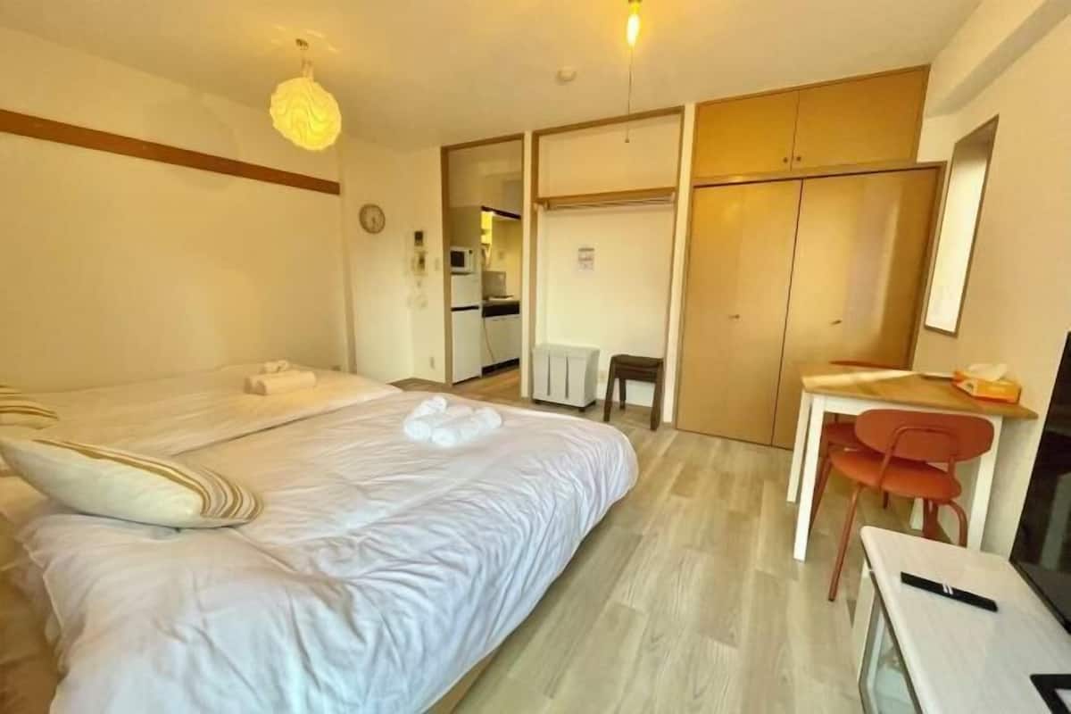 A hotel room with a bed, a desk, a chair, and a wardrobe.