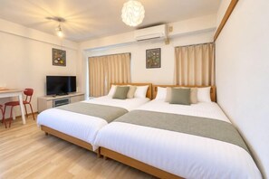 A hotel room with two beds, a desk with a television, and a chair. - YMK Oshiage 7B (Tokyo)