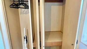 A closet with wooden doors, a hanging rack, and a vacuum cleaner. - YMK Oshiage 7B (Tokyo)