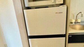 A compact kitchen with a white refrigerator labeled 'Hisense', a stainless steel sink, and a black countertop. - YMK Oshiage 7B (Tokyo)