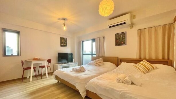 A hotel room with two beds, a desk, a chair, and a TV. - YMK Oshiage 7B (Tokyo)