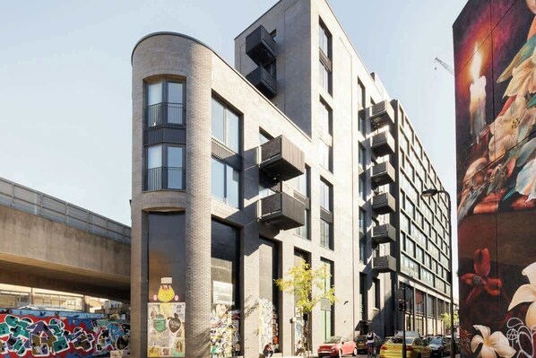 A modern building with a curved facade, large windows, and balconies. - Urban Minimalist Apartment with Private Balcony (Greater London)