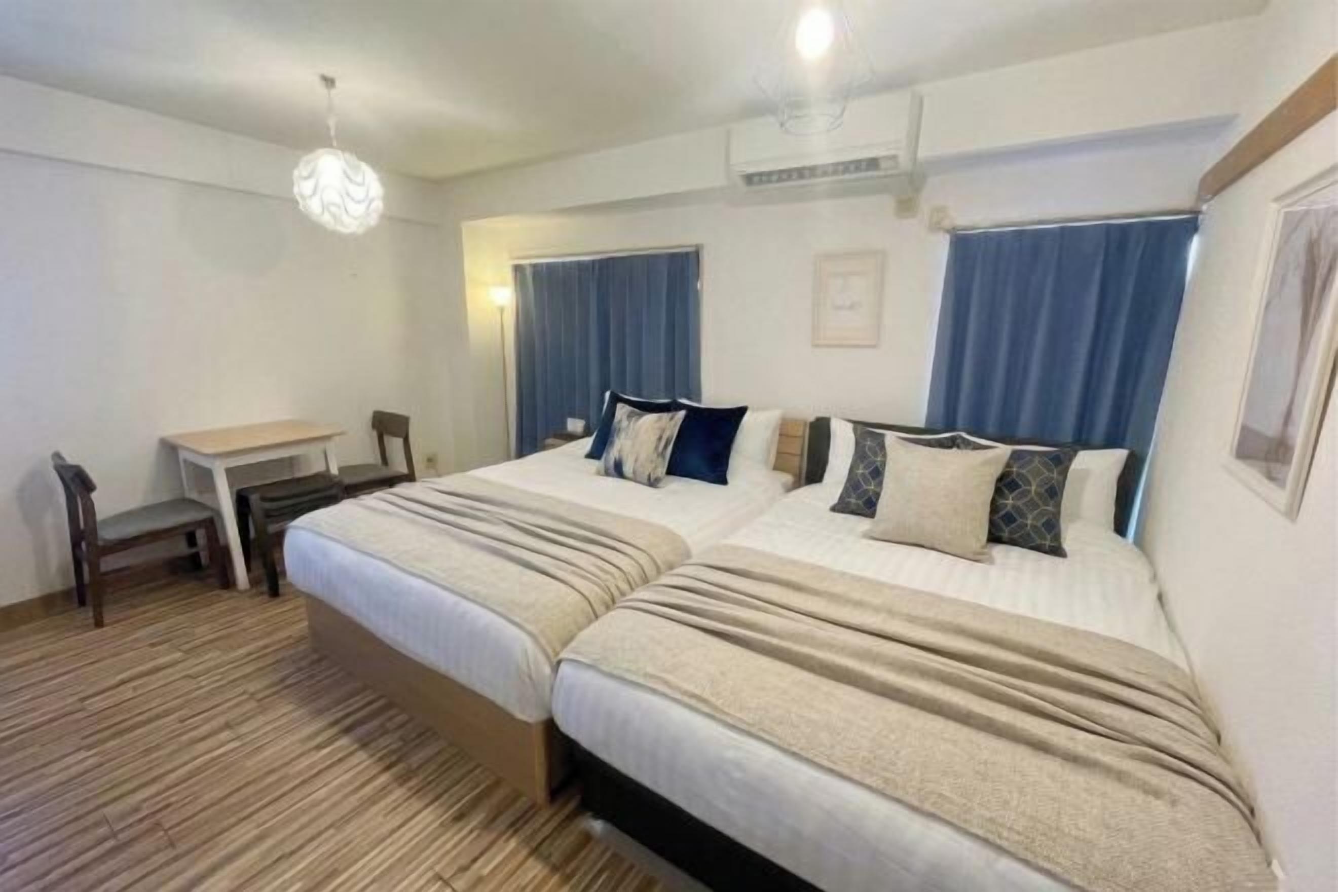 A hotel room with two beds, a desk, and a chair.
