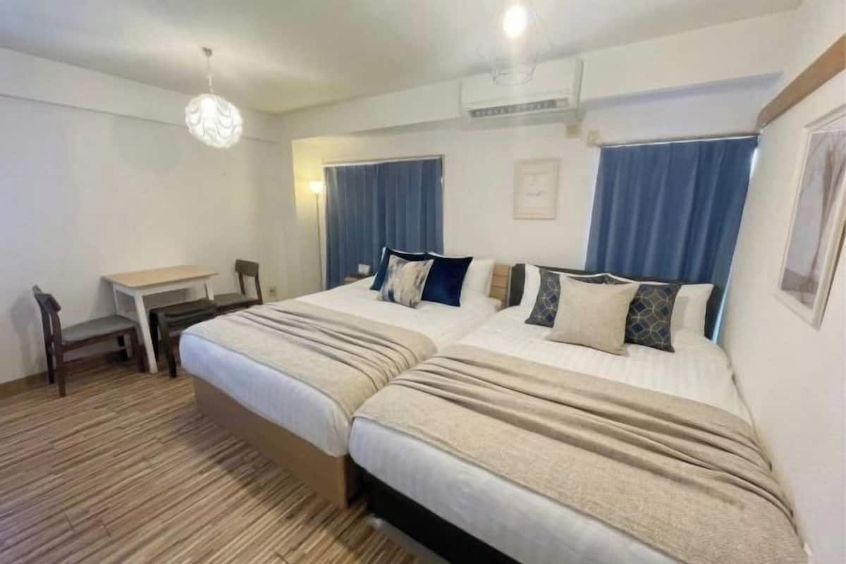 A hotel room with two beds, a desk, and a chair.