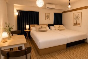 A hotel room with a double bed, a desk with a chair, a small table with a lamp, and a wall-mounted air conditioner. - YMK Oshiage 6B (Tokyo)