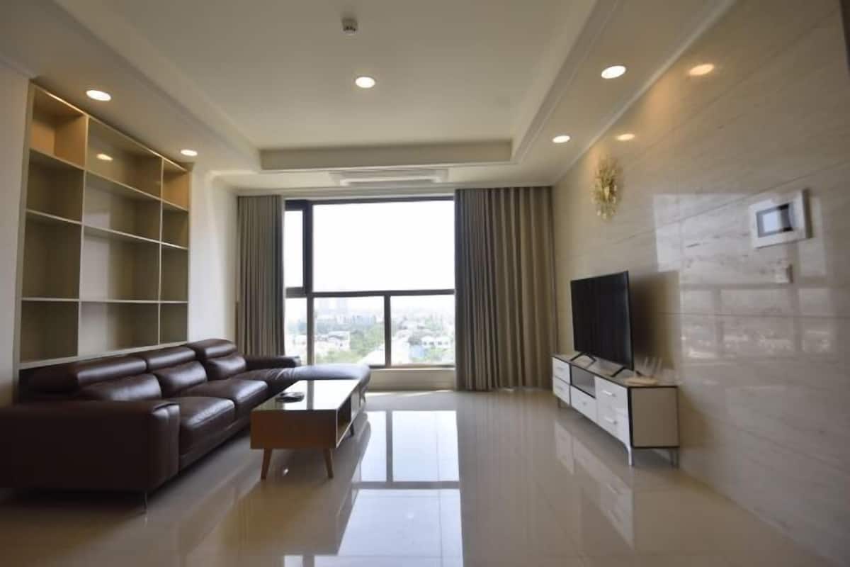 A modern living room with a leather sofa, a coffee table, a TV, and built-in shelving.