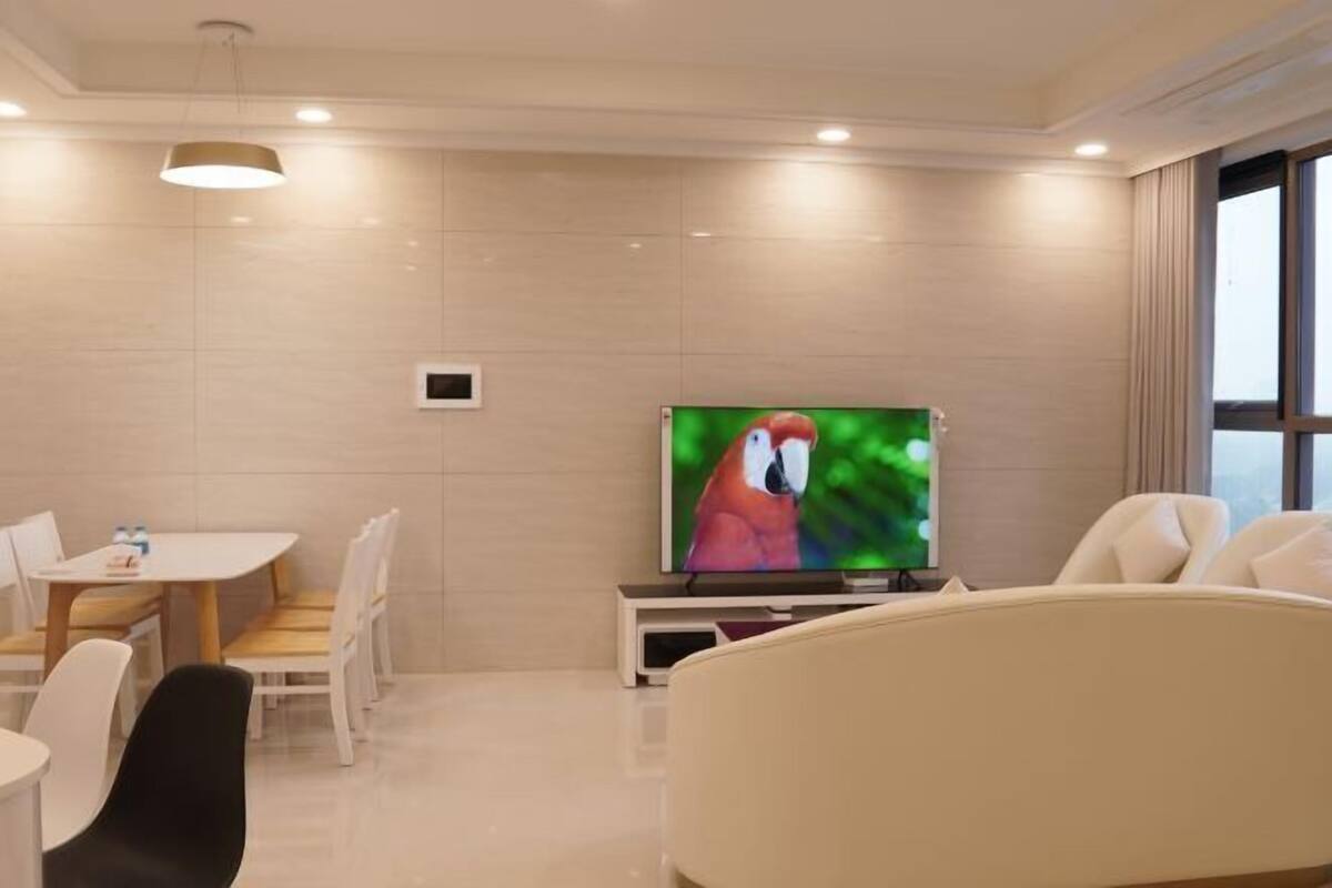 A modern room with a dining area, a flat-screen TV, and a sofa.