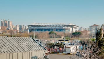 Um estádio com uma extensa área de arquibancadas e um estacionamento em primeiro plano.