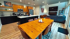 A modern kitchen with wooden cabinets, a central island, and a dining area with a wooden table and chairs.