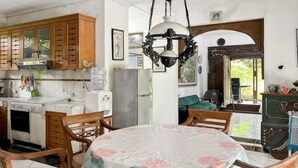 A kitchen with wooden cabinets, a dining table with chairs, a hanging light fixture, and a view through an arched doorway. - Large Bogor Villa w/ Pool, BBQ Grill& Fishing Spot (Cigombong)
