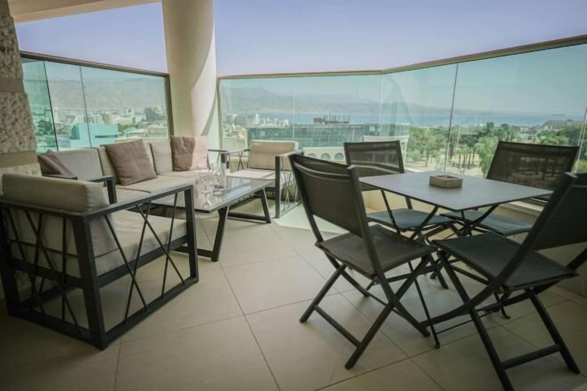 A balcony with a table and chairs, a sofa, and a view of the cityscape.