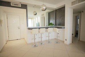 A modern kitchen with a central island, four bar stools, and pendant lighting.