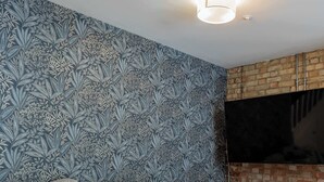 Un salon avec un canapé gris, une table basse en bois et un papier peint à motifs.