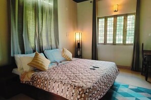 Ein Schlafzimmer mit Bett, Vorhängen, einer Wandlampe und einem Fenster mit Vorhängen.