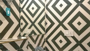 A bathroom with a geometric tile pattern, a mirror, a towel rack, and a sink. - Hoztel Jollygrrant Doon (Dehradun)