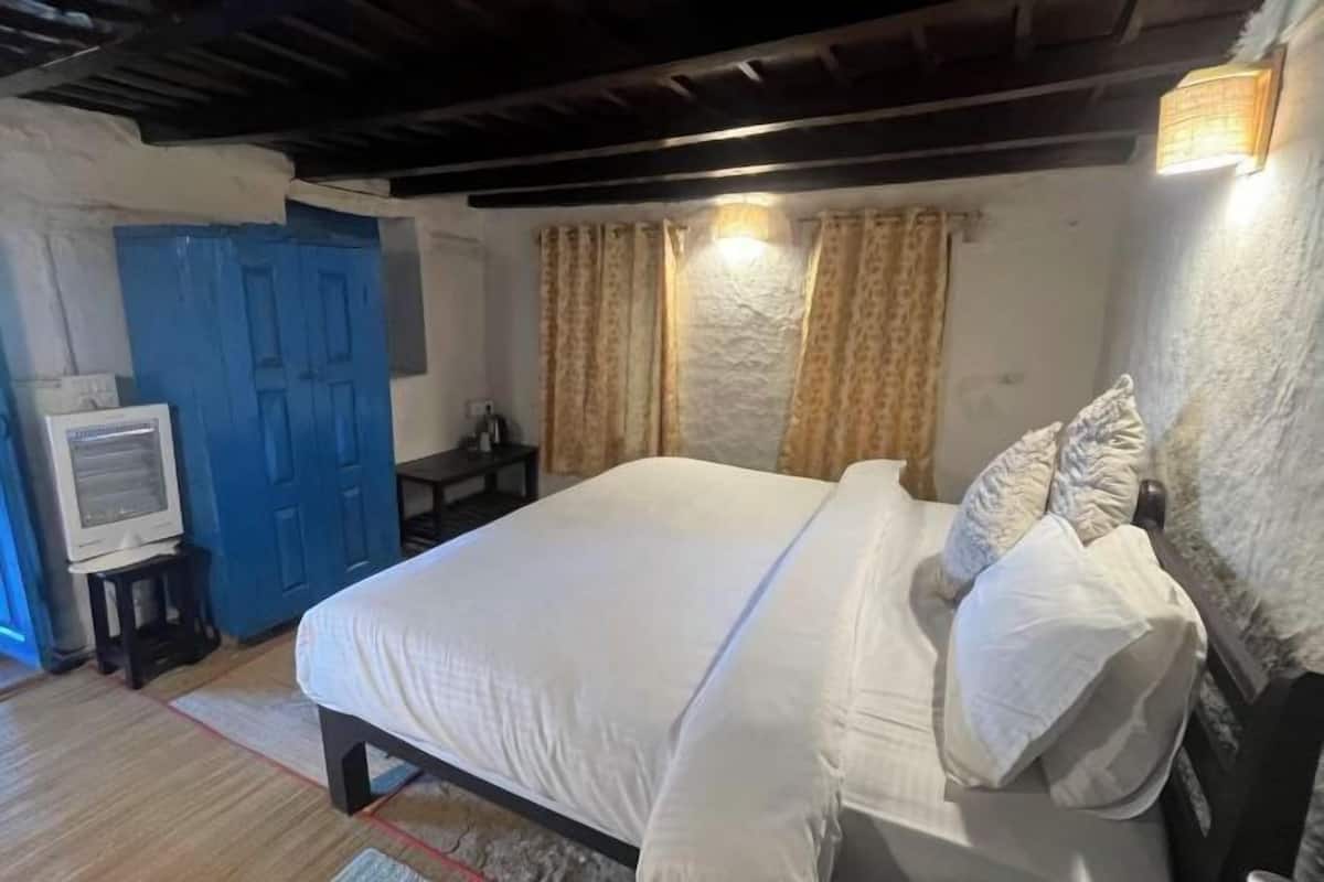 A bedroom with a bed, a blue door, a television on a small table, and curtains.