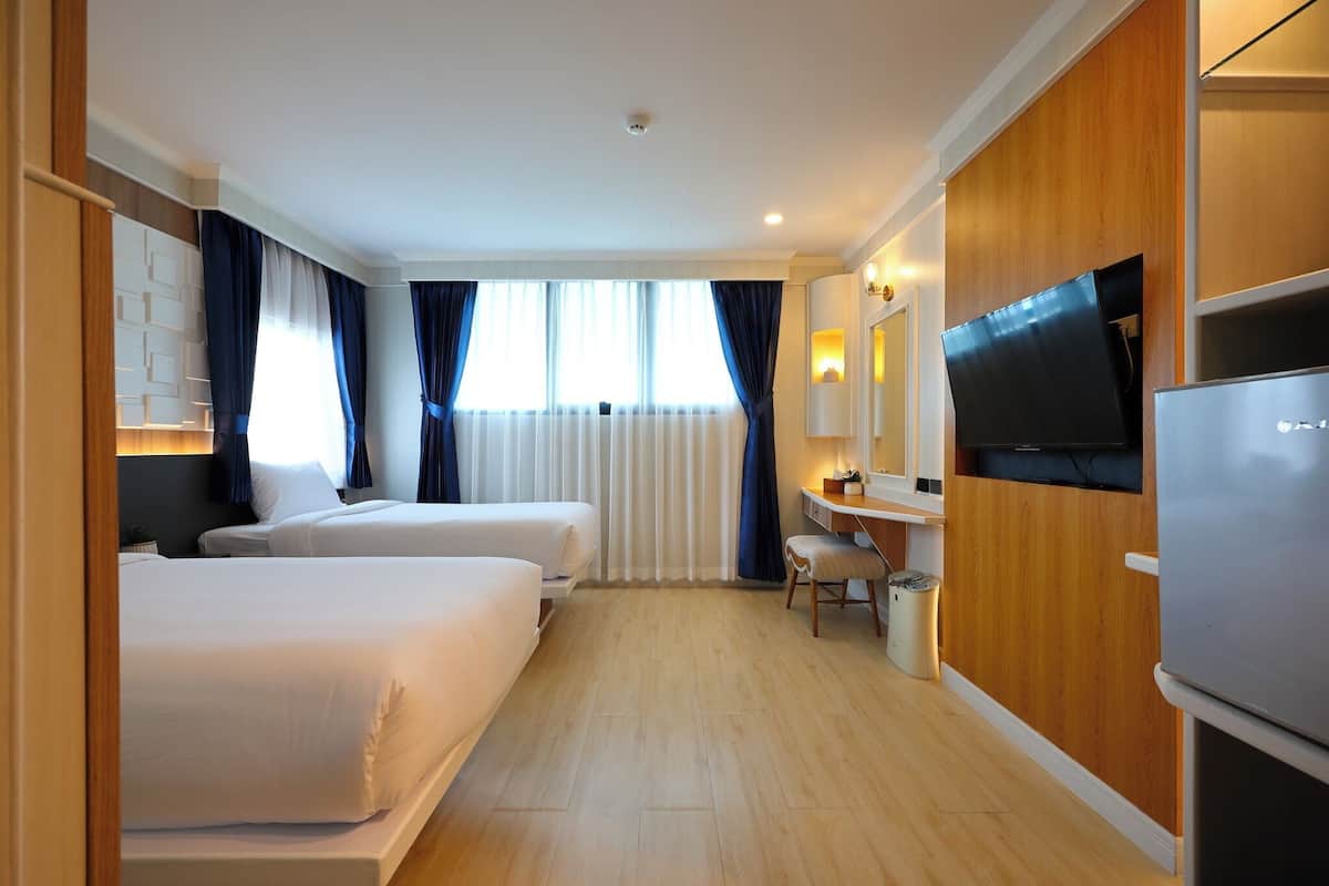 Een hotelkamer met twee bedden, een bureau, een televisie en een koelkast.