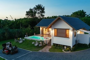 Une maison moderne dotée d’une piscine, d’un patio couvert et d’une allée.