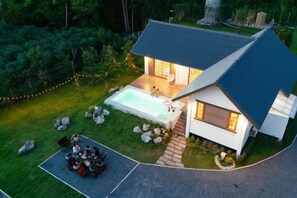 A modern house with a swimming pool, a patio with outdoor furniture, and a well-maintained lawn. - Harper Pool Villa Khaoyai 3 Bedroom, 3 Bathroom (Pak Chong)
