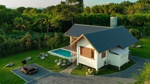 Una casa moderna con piscina, rodeada de exuberante vegetación.