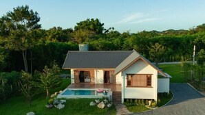 Una casa moderna con piscina, rodeada de césped cuidado y árboles.