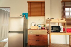 Une cuisine compacte équipée d’un réfrigérateur, d’un four à micro-ondes et d’un meuble de rangement en bois.