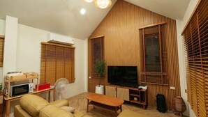 Una sala moderna con televisor de pantalla plana, persianas de madera, un sofá y un comedor.