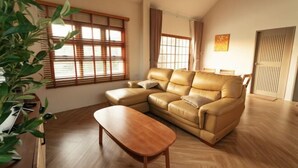 Una sala de estar con un sofá de cuero, una mesa de centro de madera y una planta en maceta.