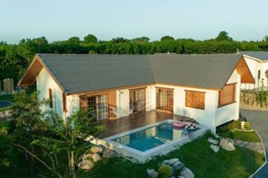 Ein modernes Haus mit Swimmingpool, großen Fenstern und einem gepflegten Rasen.